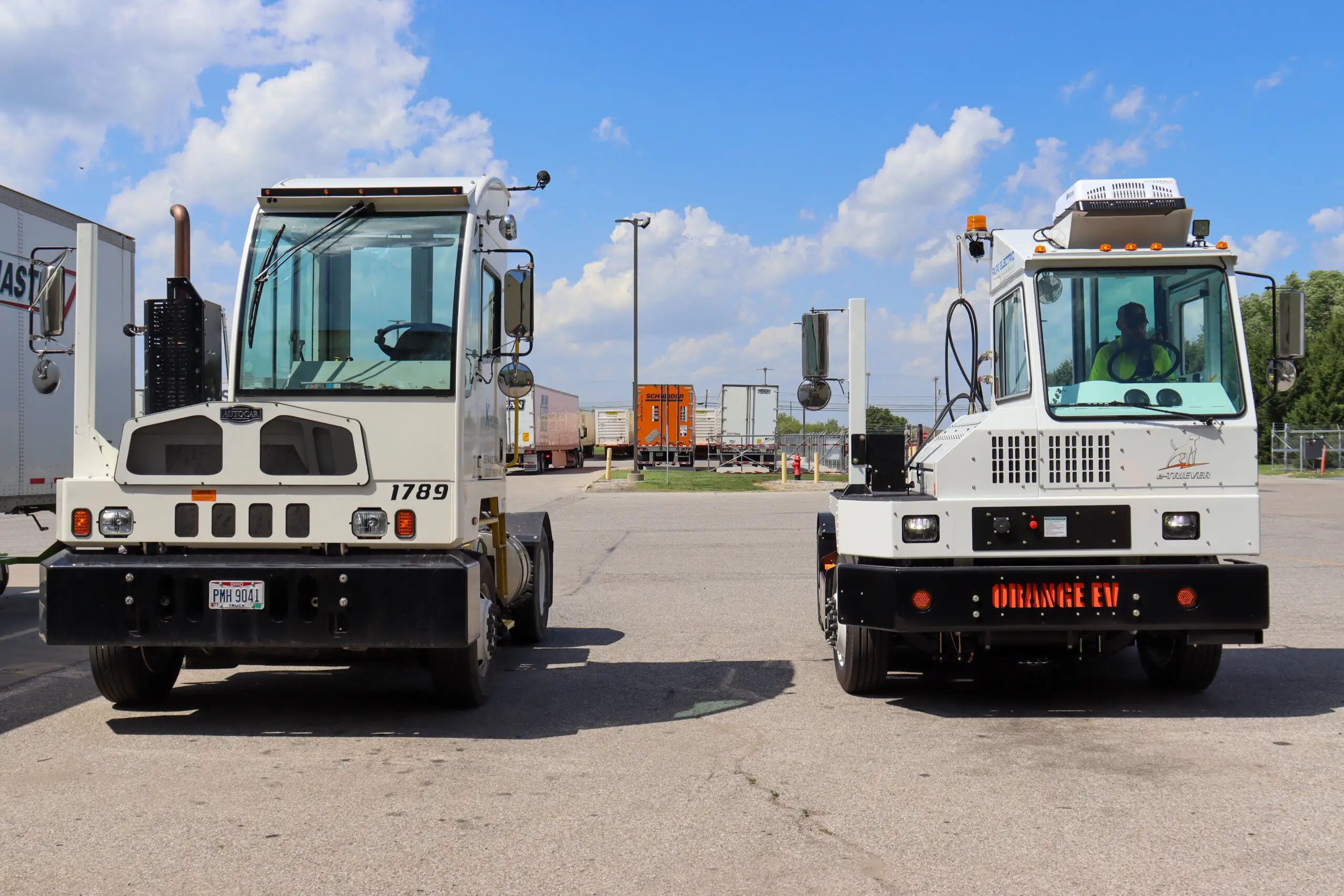 Electric yard tractor parked next to a diesel spotter truck outside