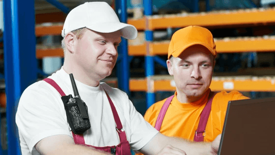 Warehouse employees smiling while looking at a screen