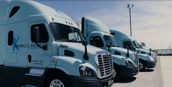 Side view of the front of several Keller Trucking trucks lined up outside