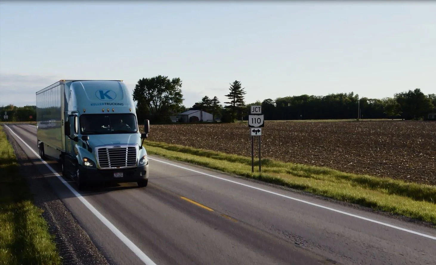 Truck from Keller Trucking driving with farmland in the background