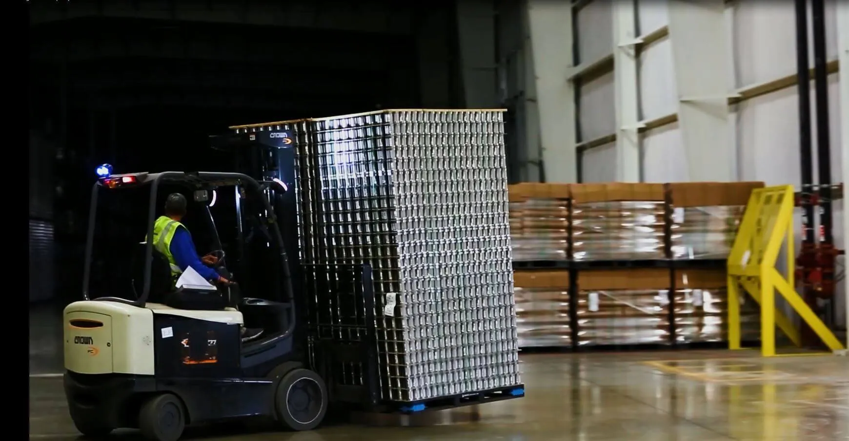 Forklift moving pallets of cans through a warehouse