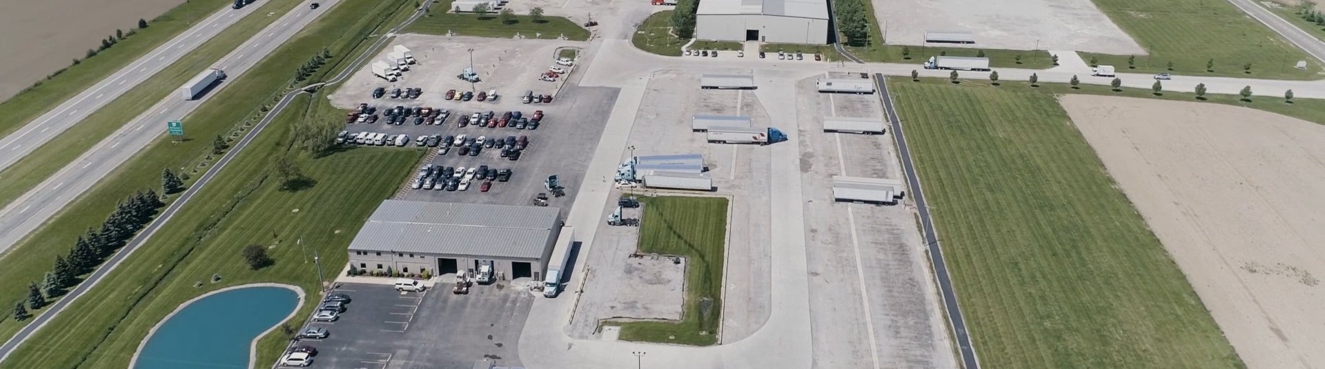 Warehouse and trucks in rural area from sky view