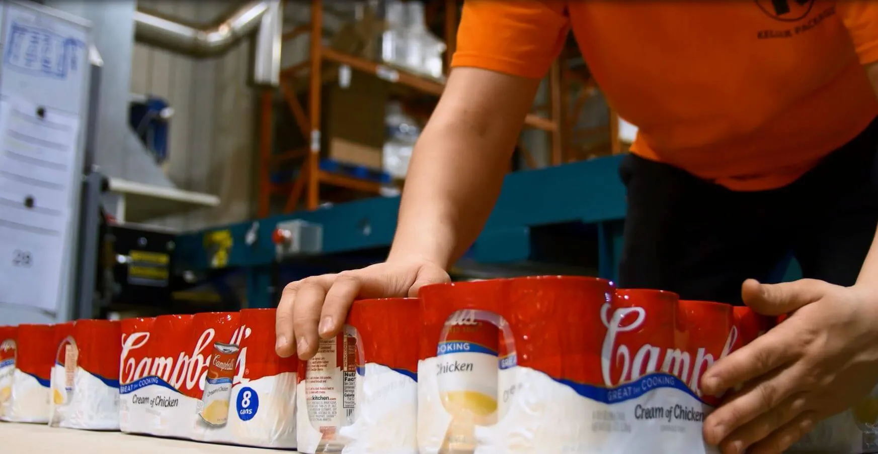 Several 8-packs of Campbell's cream of chicken soup in packaging being handled