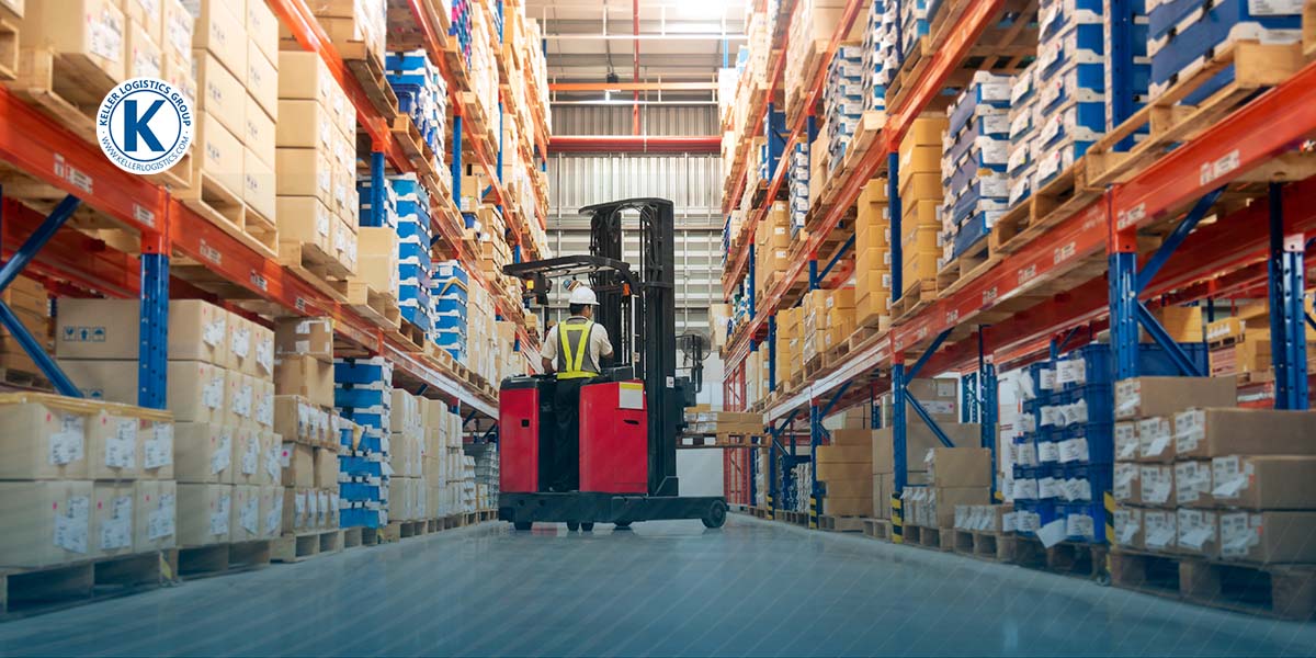 A worker drives a forklift through a warehouse.